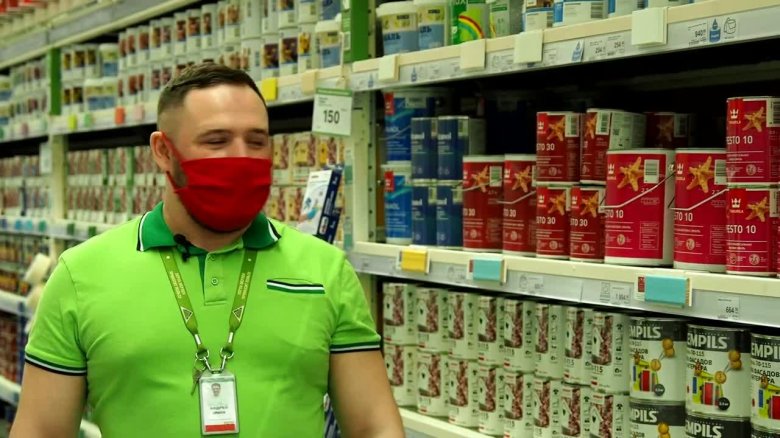 Человек рассматривает банку краски в Леруа