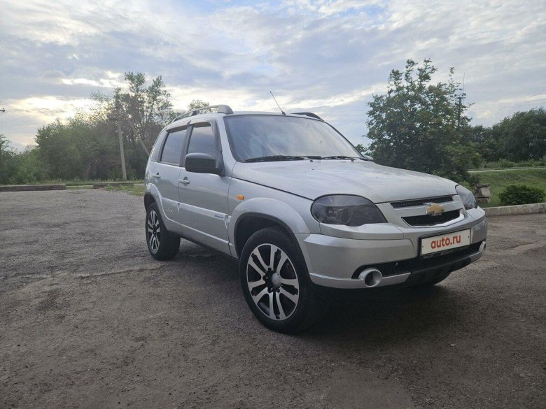 Серебристая Шевроле Нива в лесу